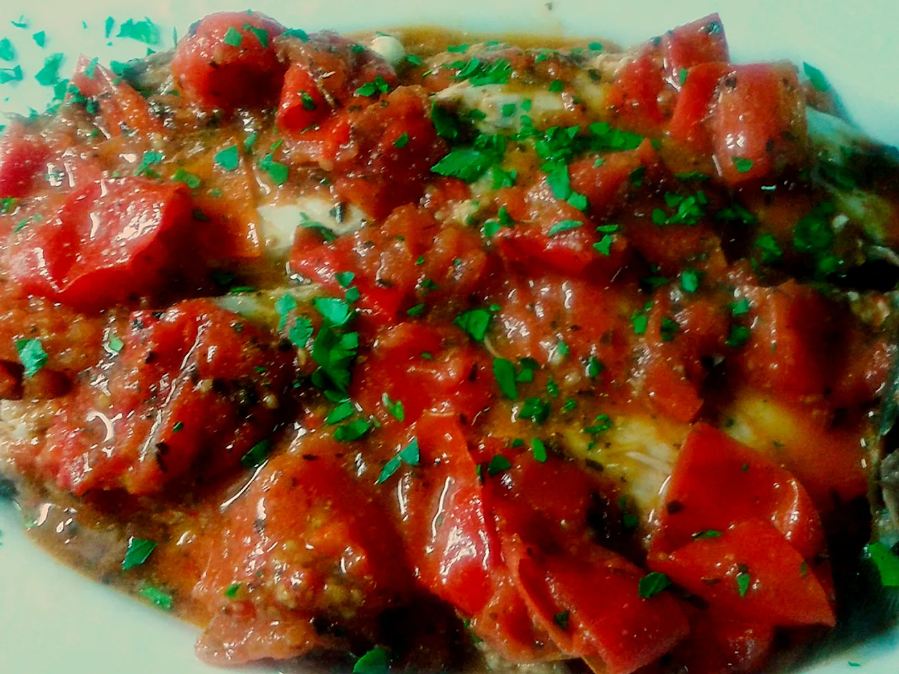 Filetti di pesce in umido con pomodoro fresco a pezzi e prezzemolo