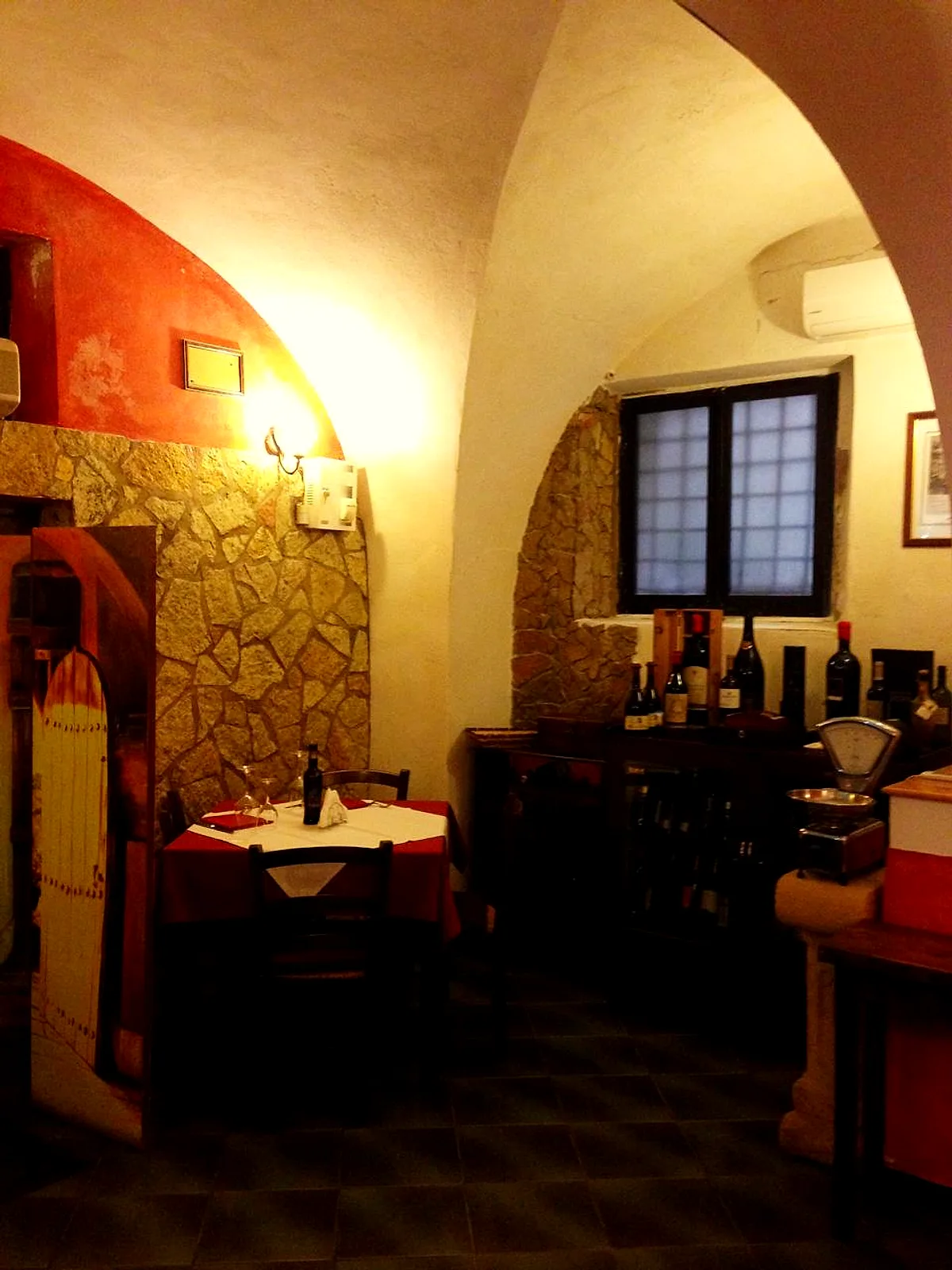 Un tavolo per due sotto la volta, accanto alla vetrina dei vini e a una vecchia bilancia