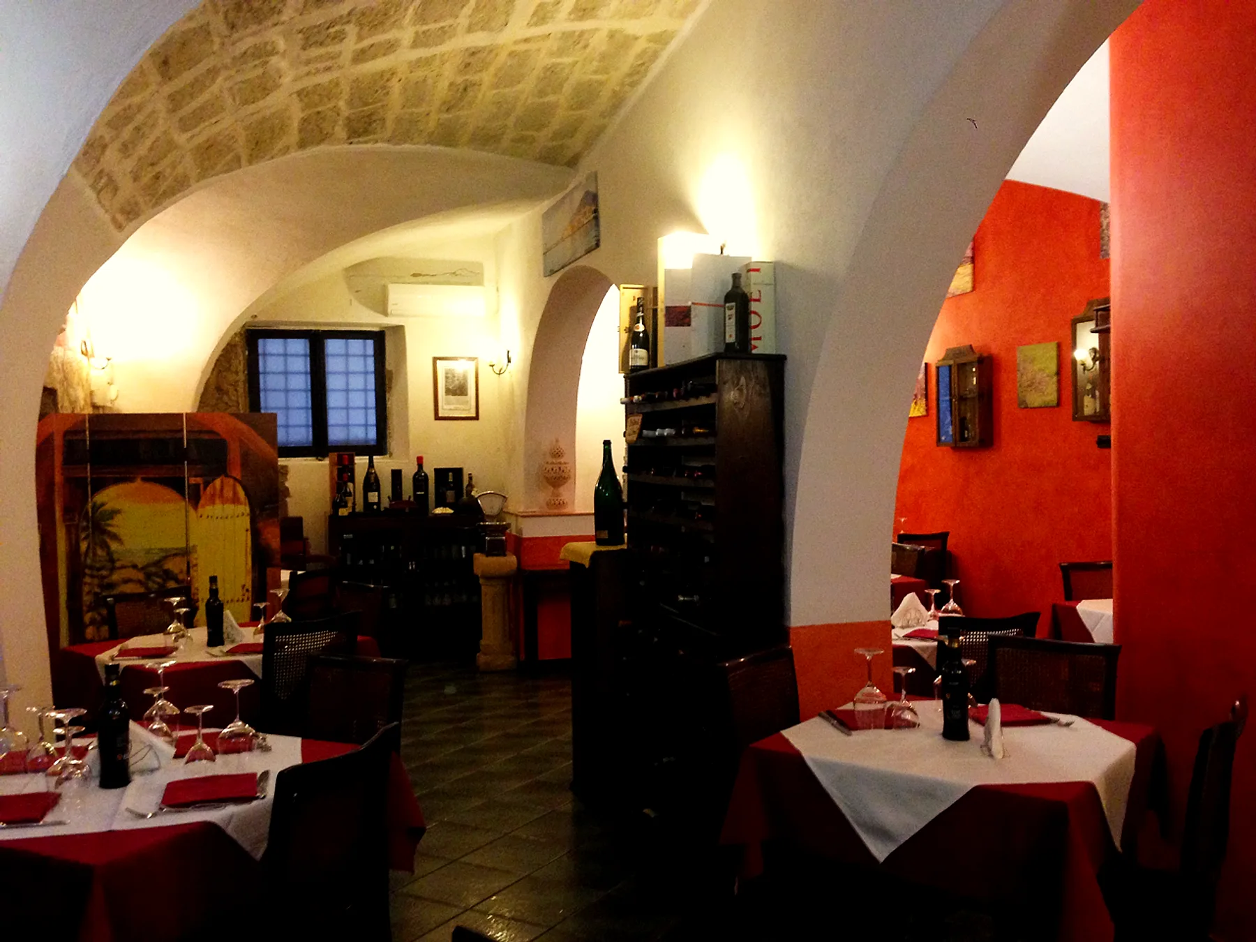 La volta in blocchi di tufo, la rastrelliera dei vini e i tavoli apparecchiati nella sala